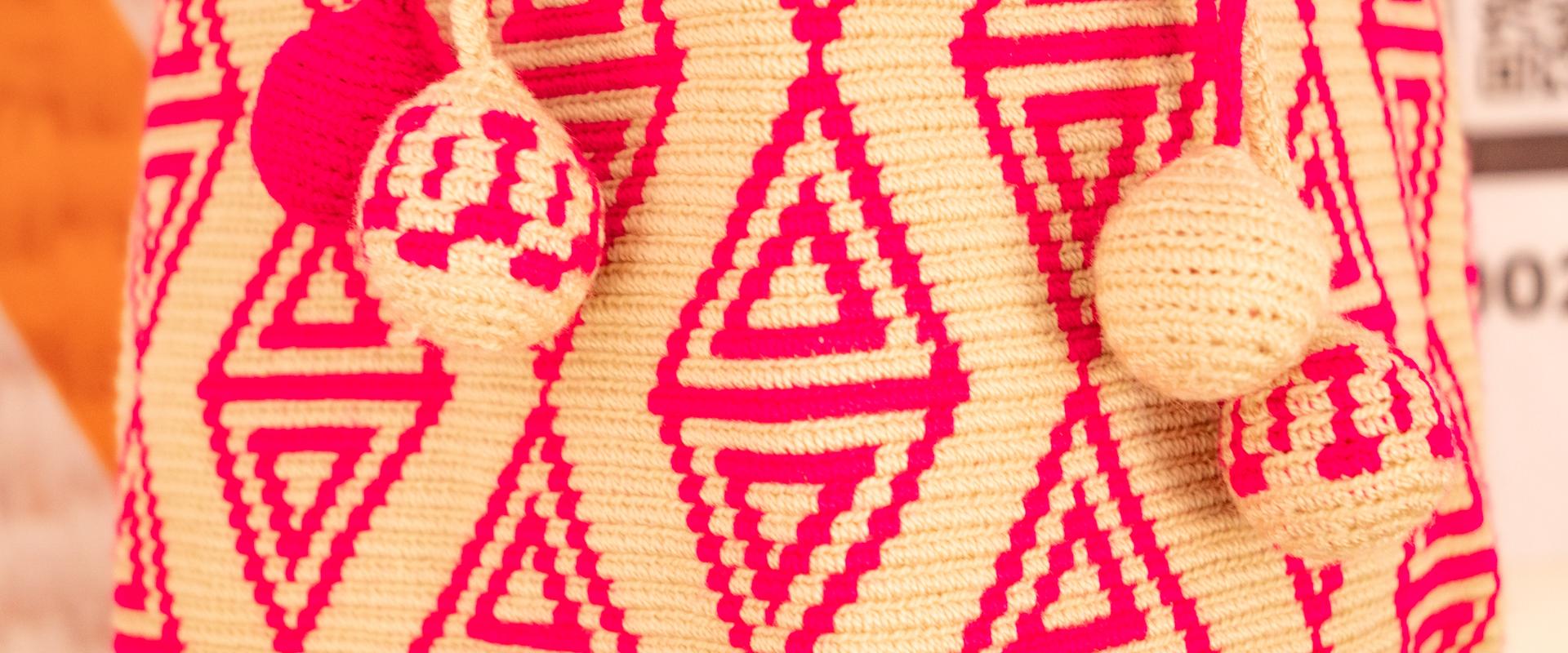 Detalle de mochila wayúu tejida con patrones geométricos en rosa y crema